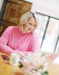 a lady in pink shirt working on laptop