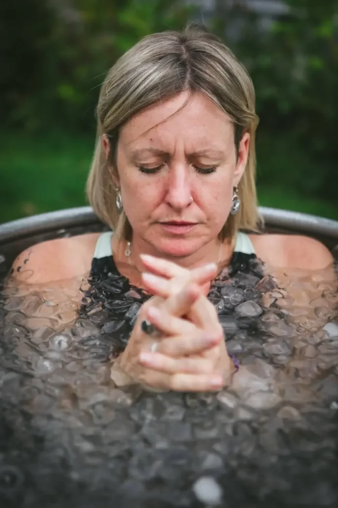 Woman meditating in an ice bath surrounded by ice cubes.