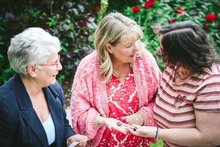 Three women enjoying a lively conversation in a garden setting.